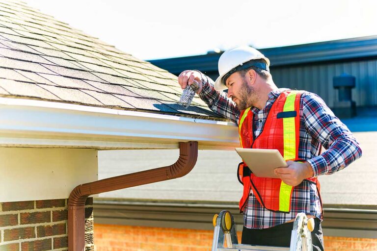 A roofing crew removing old shingles and installing new materials on a suburban house on a sunny day.