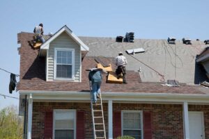 A person inspecting shingles on a residential roof with a basketball resting nearby.