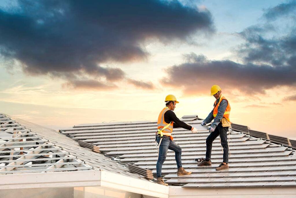 A roofing worker repairing asphalt shingles on a sloped house roof in daylight.